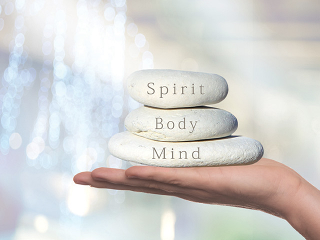 Hand holding stones with the words mind and body on them.